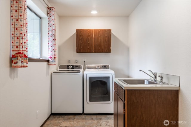 clothes washing area with a sink, cabinet space, and washer and clothes dryer