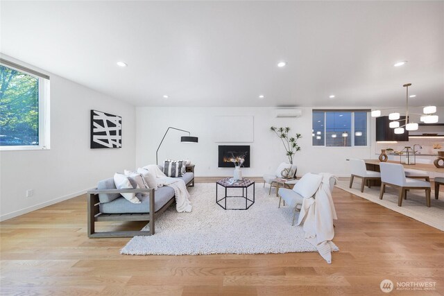 living room with a wall mounted air conditioner, wood finished floors, baseboards, an inviting chandelier, and recessed lighting