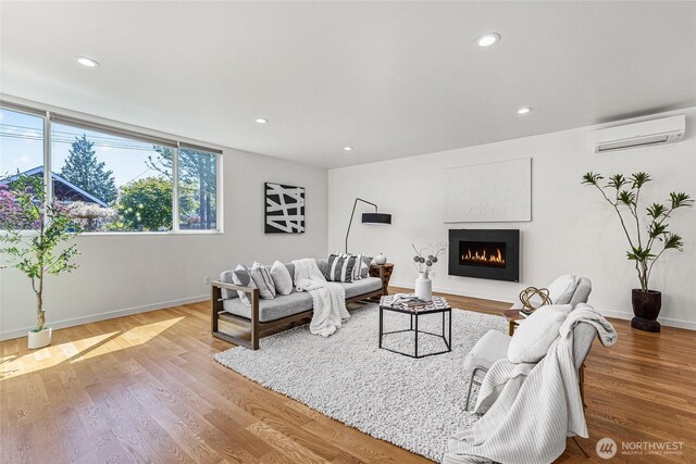 living area with recessed lighting, a warm lit fireplace, baseboards, and a wall mounted air conditioner