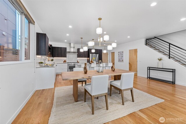 dining room with light wood-type flooring, recessed lighting, baseboards, and stairway