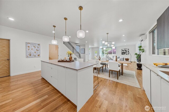 kitchen featuring light countertops, light wood-style flooring, a kitchen island, and white cabinetry