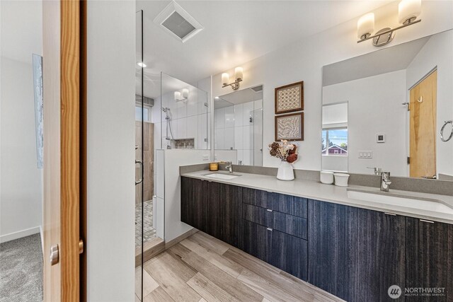 full bathroom featuring double vanity, visible vents, a shower stall, and a sink