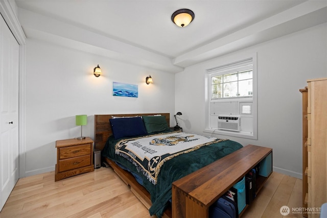 bedroom with baseboards, cooling unit, a closet, and light wood finished floors