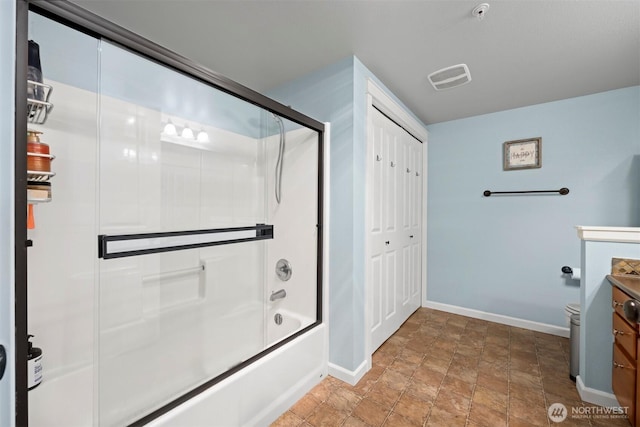bathroom featuring vanity, baseboards, combined bath / shower with glass door, and stone finish floor