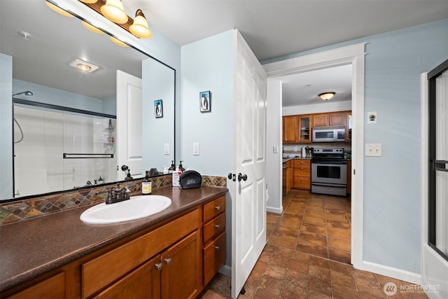 bathroom featuring vanity, baseboards, and a shower with shower door