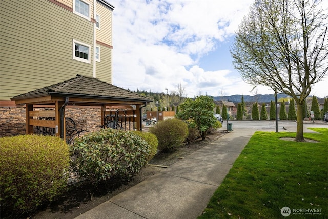 surrounding community with a lawn, a mountain view, and a gazebo