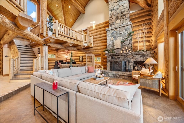 living room featuring stairway, log walls, a high ceiling, and a stone fireplace