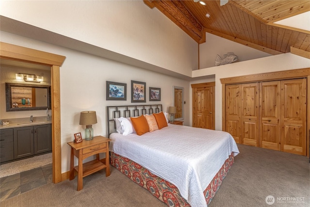 bedroom with beam ceiling, ensuite bath, high vaulted ceiling, dark colored carpet, and wooden ceiling
