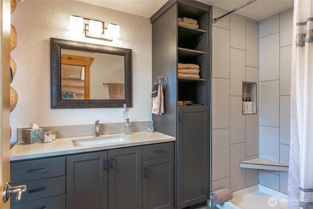 bathroom featuring a shower with curtain, a textured wall, and vanity
