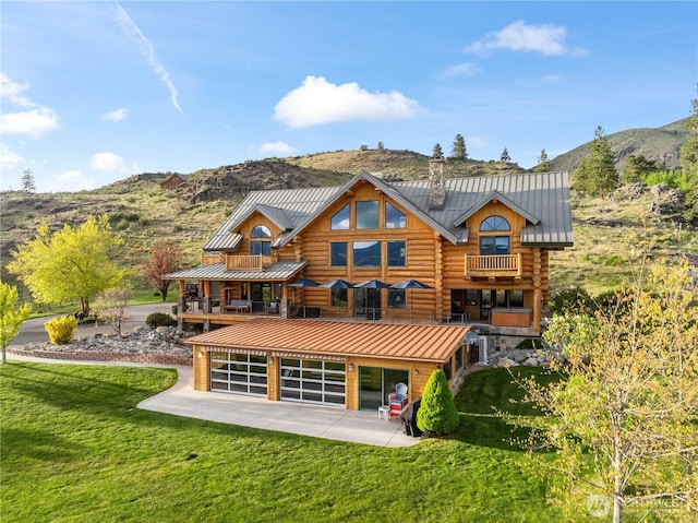 rear view of property featuring a lawn, log exterior, and a mountain view