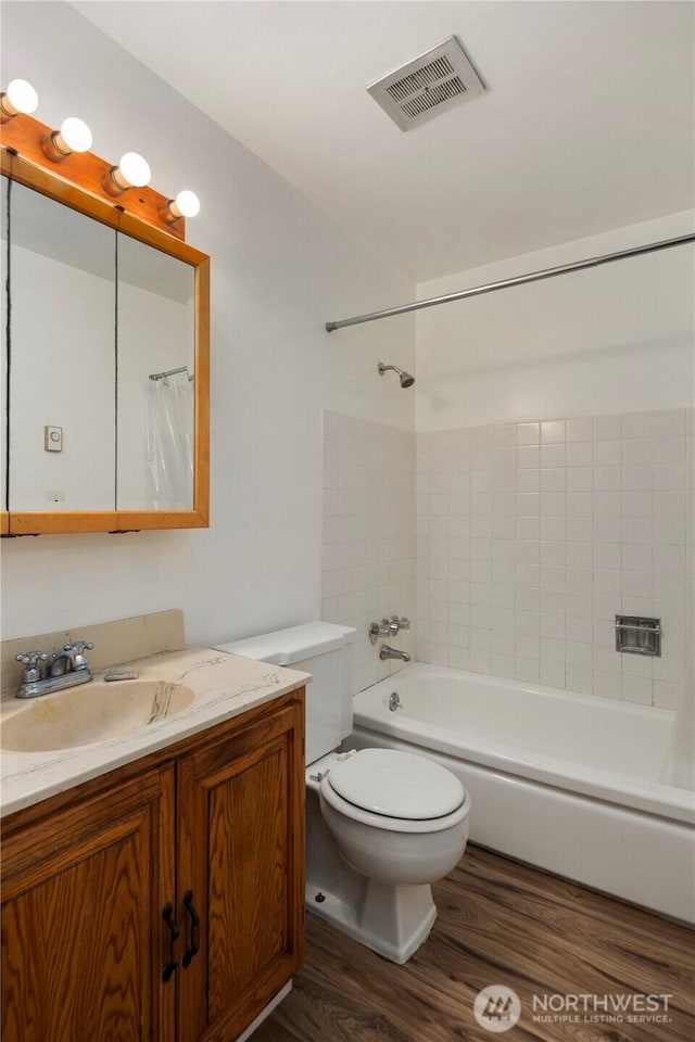 full bath featuring visible vents, vanity, wood finished floors, toilet, and shower / bath combo