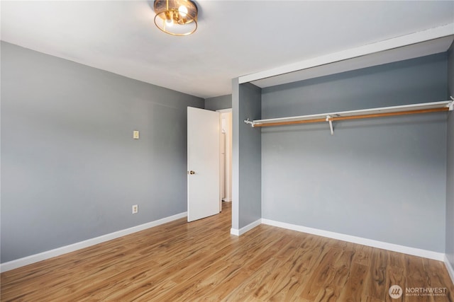 unfurnished bedroom with baseboards, a closet, and wood finished floors