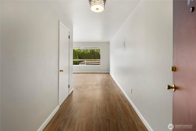 corridor featuring baseboards and wood finished floors