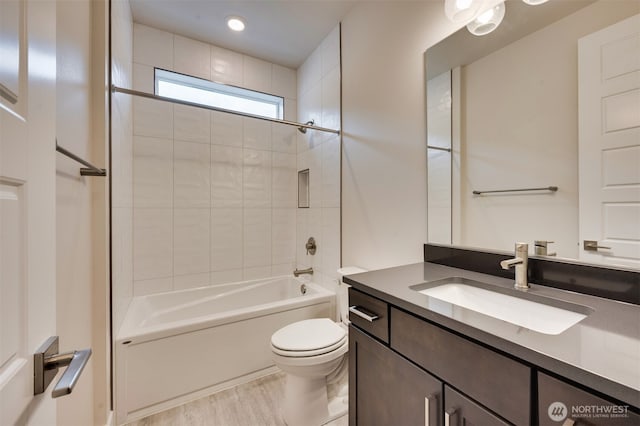 bathroom featuring vanity, washtub / shower combination, toilet, and wood finished floors