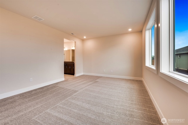 empty room with baseboards, light carpet, recessed lighting, and visible vents