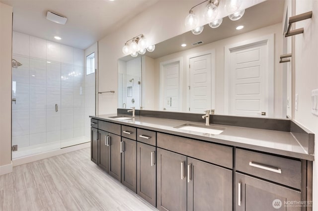 bathroom featuring visible vents, a sink, double vanity, and a shower stall