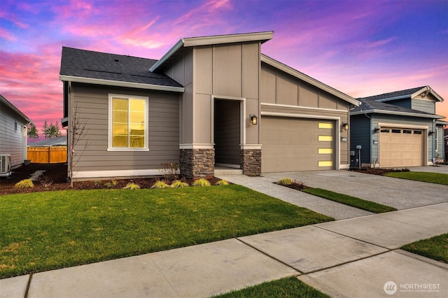view of front of home with board and batten siding, a lawn, concrete driveway, an attached garage, and stone siding