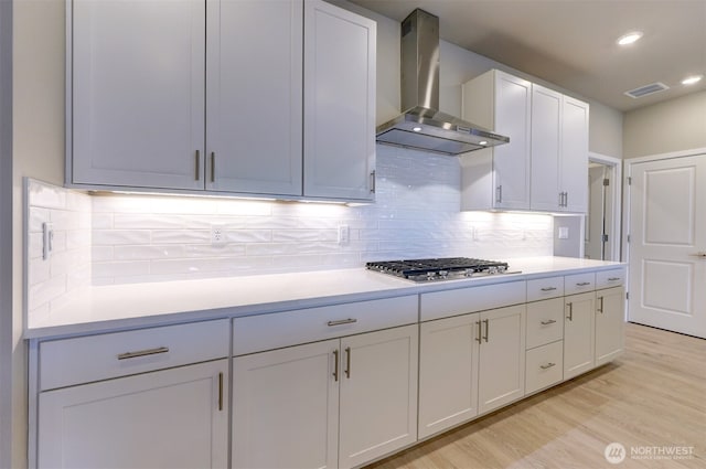 kitchen with visible vents, light countertops, wall chimney exhaust hood, and stainless steel gas cooktop