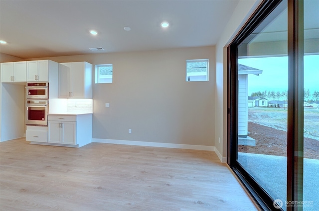 kitchen featuring visible vents, double oven, light wood-style flooring, and a wealth of natural light