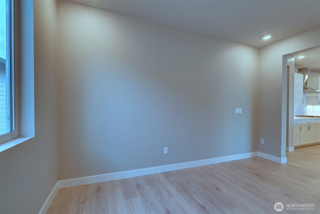 empty room featuring recessed lighting, baseboards, and light wood finished floors