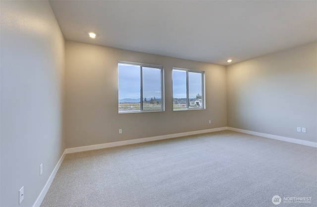spare room featuring light colored carpet, recessed lighting, and baseboards