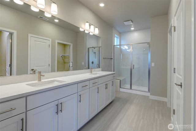 full bathroom with double vanity, visible vents, a shower stall, and a sink