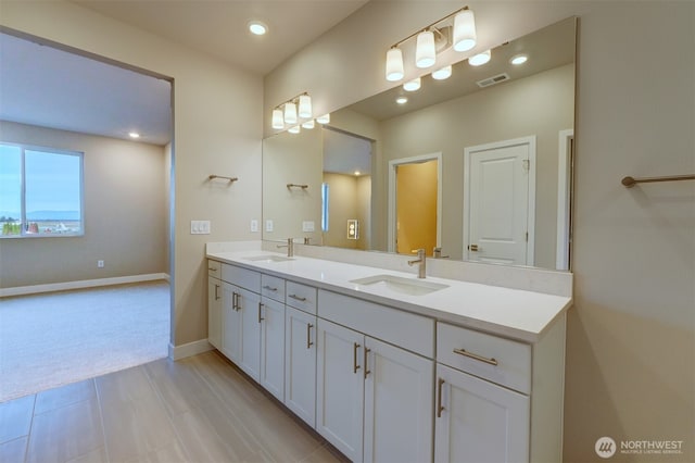 bathroom with a sink, baseboards, double vanity, and visible vents