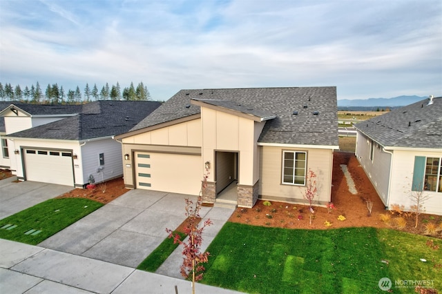 ranch-style house with a front lawn, roof with shingles, board and batten siding, concrete driveway, and an attached garage
