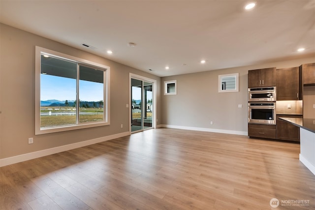 unfurnished living room featuring baseboards, light wood finished floors, recessed lighting, and visible vents