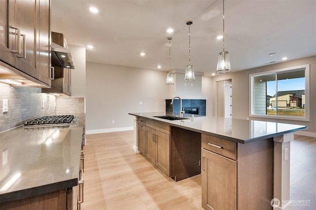 kitchen with baseboards, tasteful backsplash, a sink, and light wood-type flooring