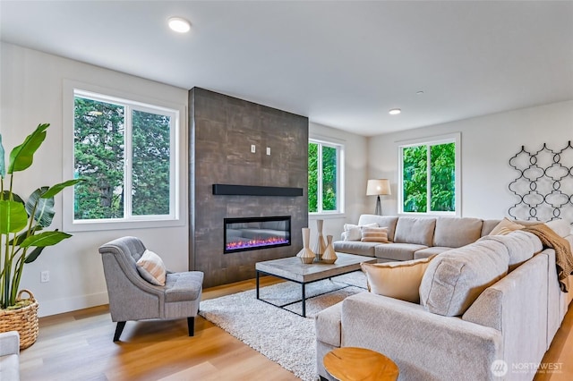 living room with light wood-style flooring, a fireplace, baseboards, and recessed lighting