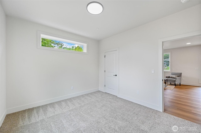 unfurnished bedroom featuring multiple windows, carpet, and baseboards
