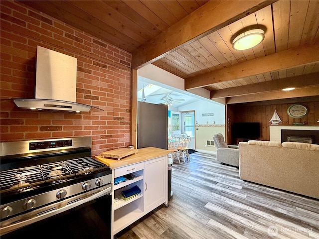 kitchen featuring stainless steel gas range, white cabinets, wood counters, wall chimney exhaust hood, and wood ceiling
