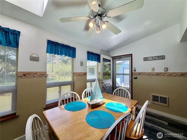 dining area featuring visible vents, wood finished floors, baseboards, vaulted ceiling with skylight, and a ceiling fan
