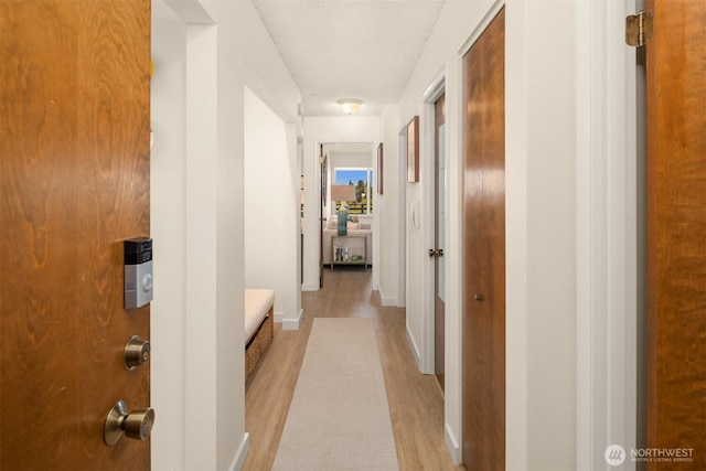 hall featuring baseboards and light wood-style floors