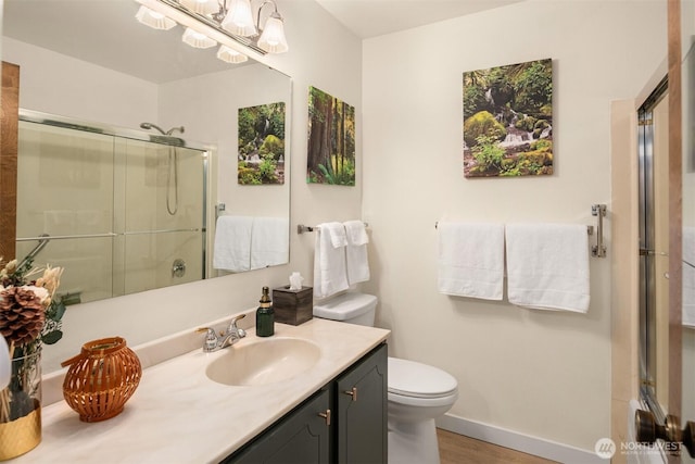 bathroom featuring a stall shower, wood finished floors, vanity, baseboards, and toilet