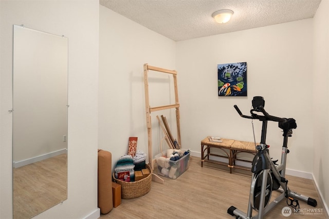 workout room featuring baseboards, a textured ceiling, and wood finished floors