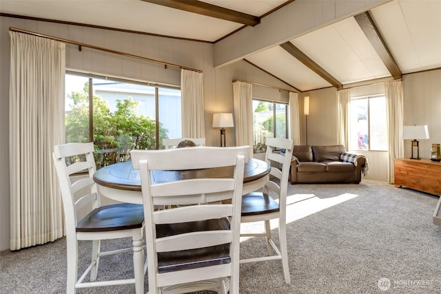 carpeted dining space with vaulted ceiling with beams
