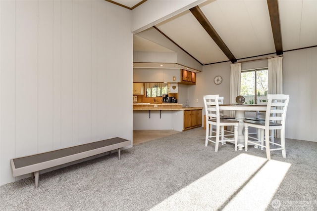 dining area with carpet floors and lofted ceiling with beams