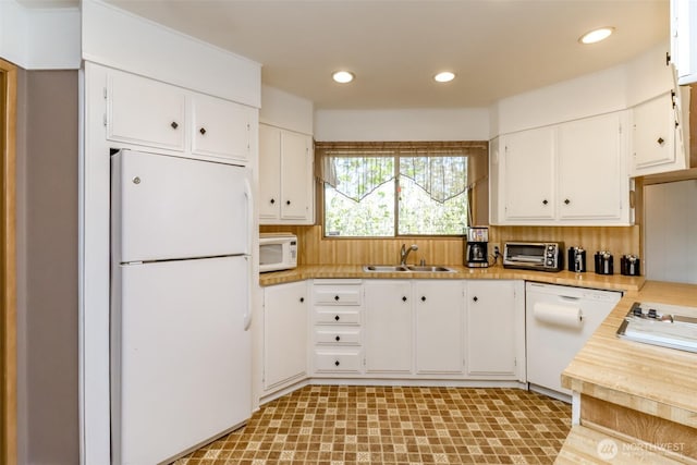 kitchen with white appliances, white cabinets, a sink, and light countertops