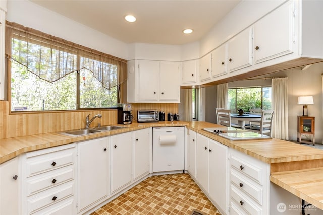 kitchen featuring dishwasher, a sink, a toaster, white cabinets, and recessed lighting