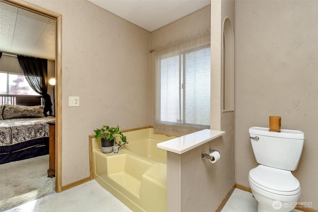ensuite bathroom featuring toilet, baseboards, ensuite bathroom, and a bath