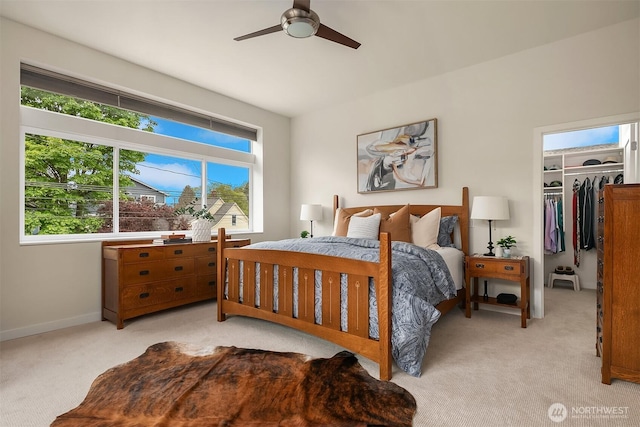 bedroom featuring multiple windows, light carpet, and a spacious closet