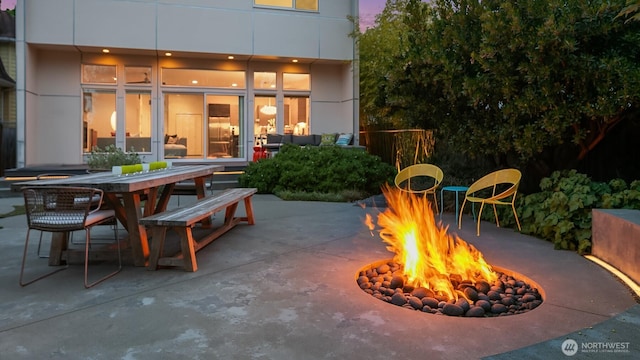 patio terrace at dusk with an outdoor fire pit and outdoor dining space
