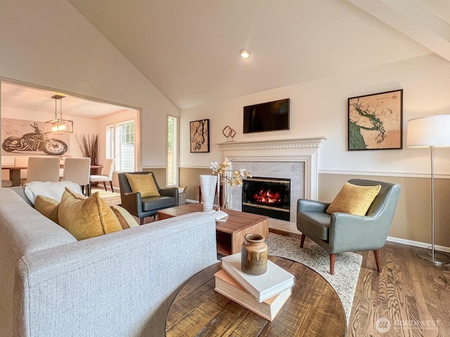 living area featuring wood finished floors, baseboards, high vaulted ceiling, a notable chandelier, and a premium fireplace