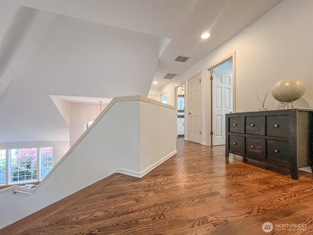 corridor with visible vents, recessed lighting, wood finished floors, and an upstairs landing