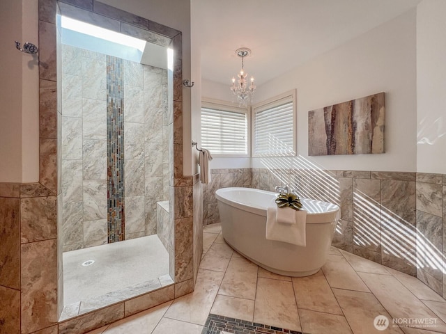 full bath featuring a walk in shower, a notable chandelier, a wainscoted wall, a freestanding tub, and tile walls
