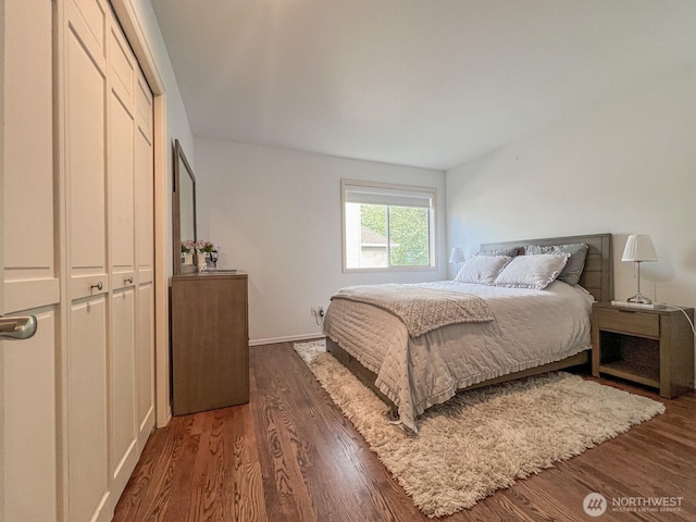 bedroom featuring baseboards, wood finished floors, and a closet