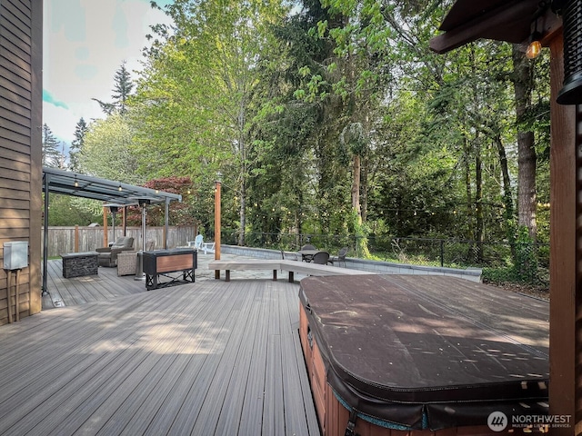 deck with a hot tub and a fenced backyard