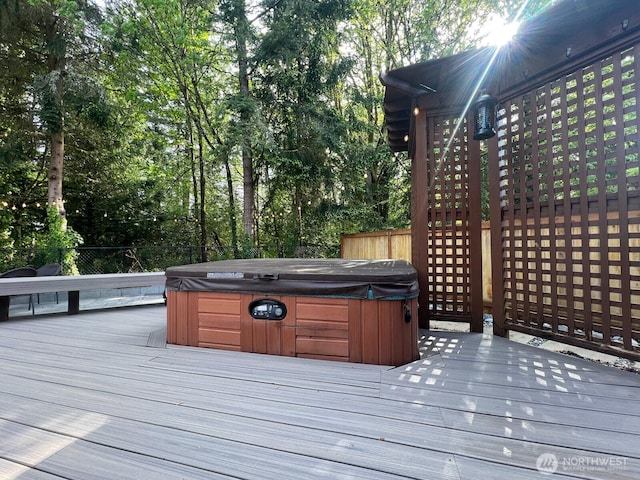 wooden deck with a hot tub and fence